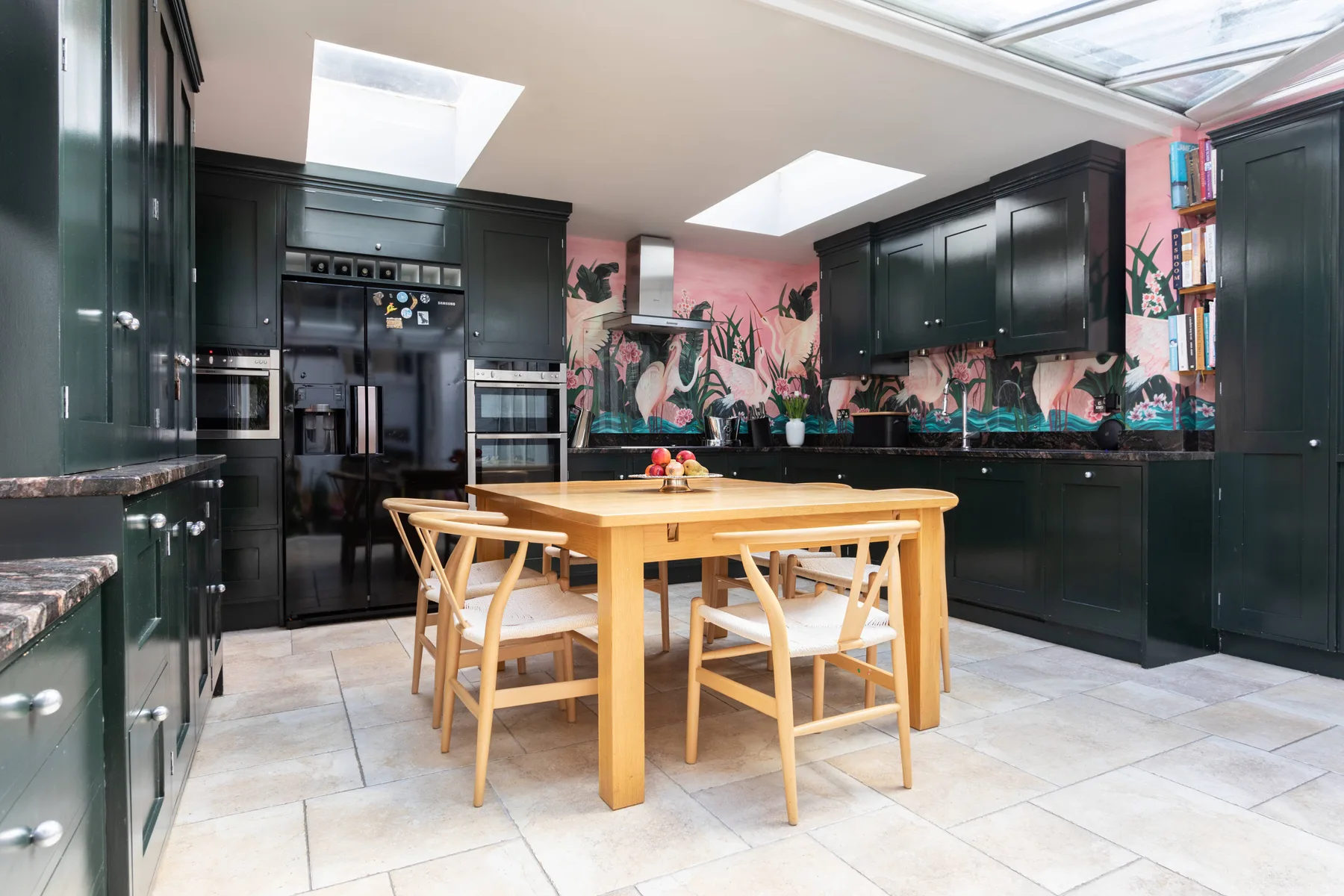 A spacious kitchen with dark cabinets, skylights, and a wooden dining table.