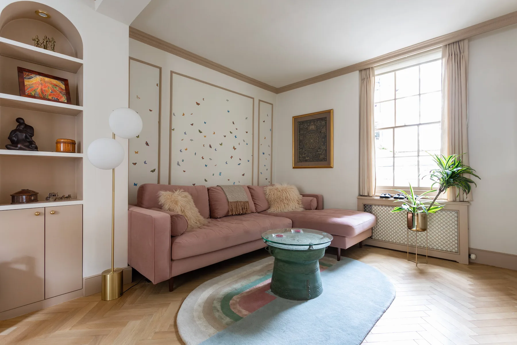 A living room with a pink sectional sofa, round coffee table, and large window.