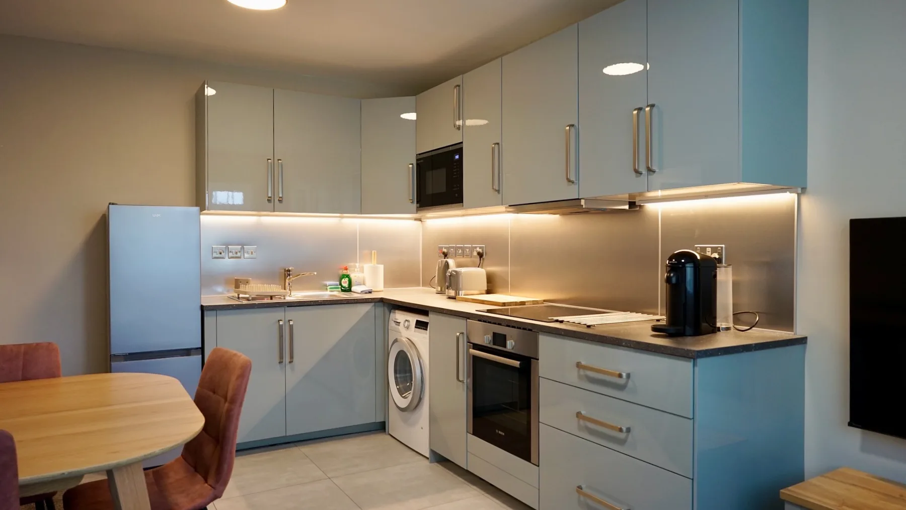 Una cocina moderna con gabinetes azules, refrigerador y electrodomésticos integrados.