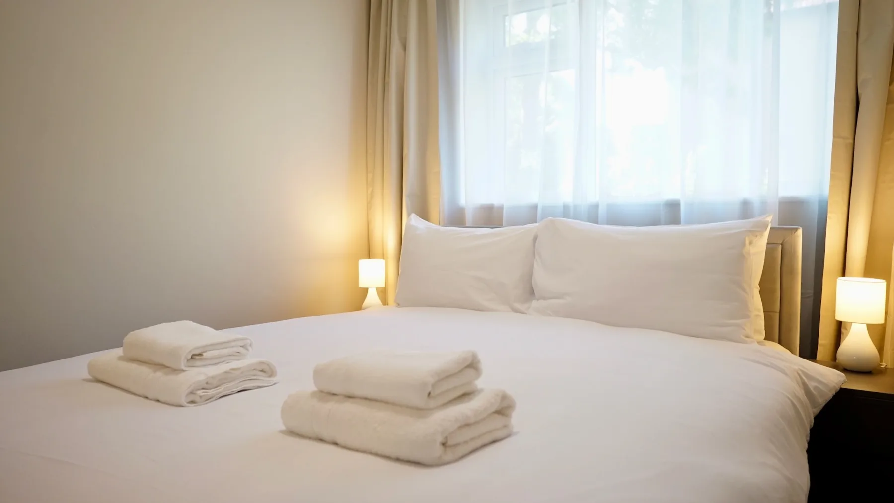 Un dormitorio con una cama bien tendida y toallas dobladas.