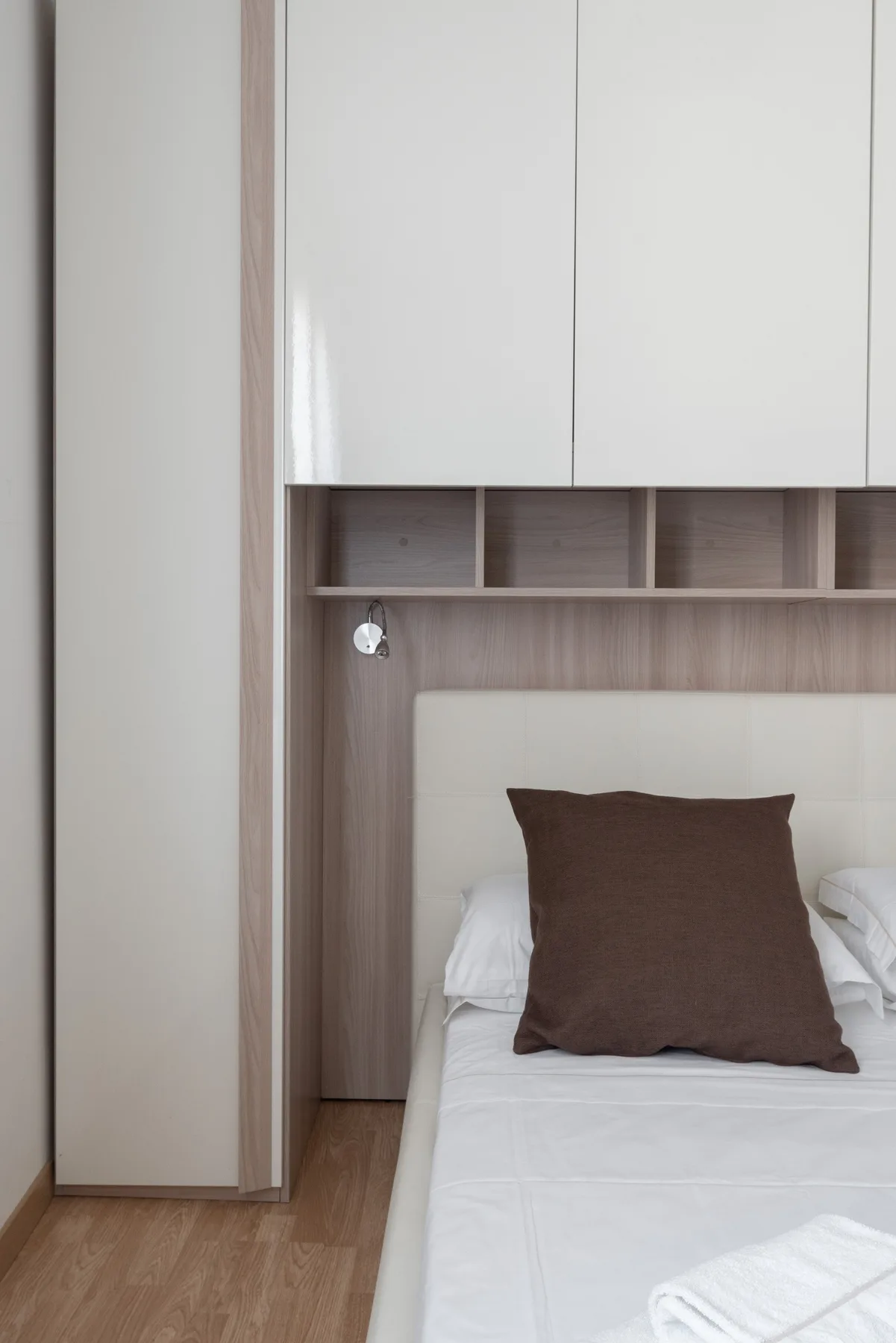 Dormitorio con una cama bajo armarios empotrados y estantes abiertos.