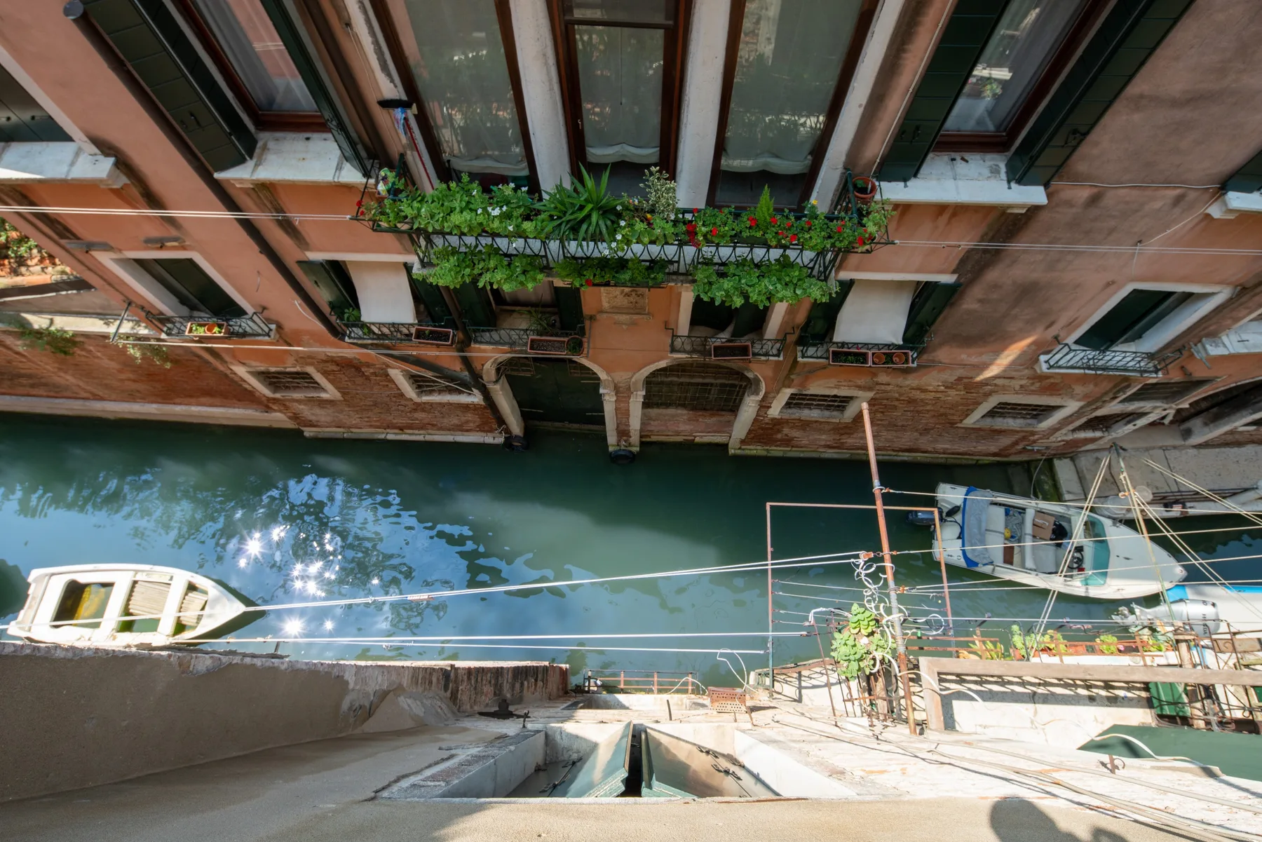 Un canal pasa junto a una hilera de edificios frente al agua, con balcones y vegetación.