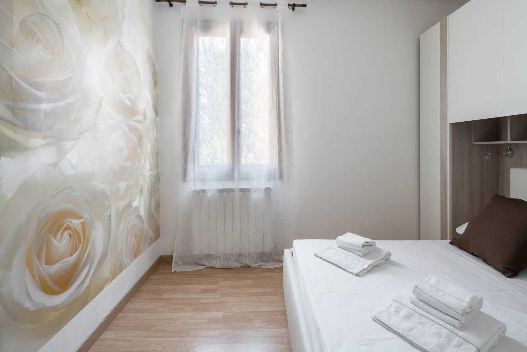 Un dormitorio con una cama blanca junto a un gran mural floral.