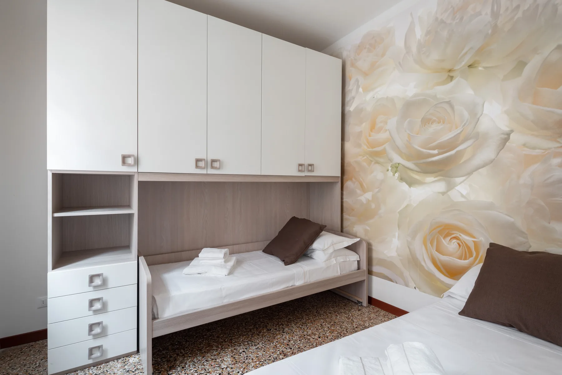 Un dormitorio con camas integradas y un gran mural floral.