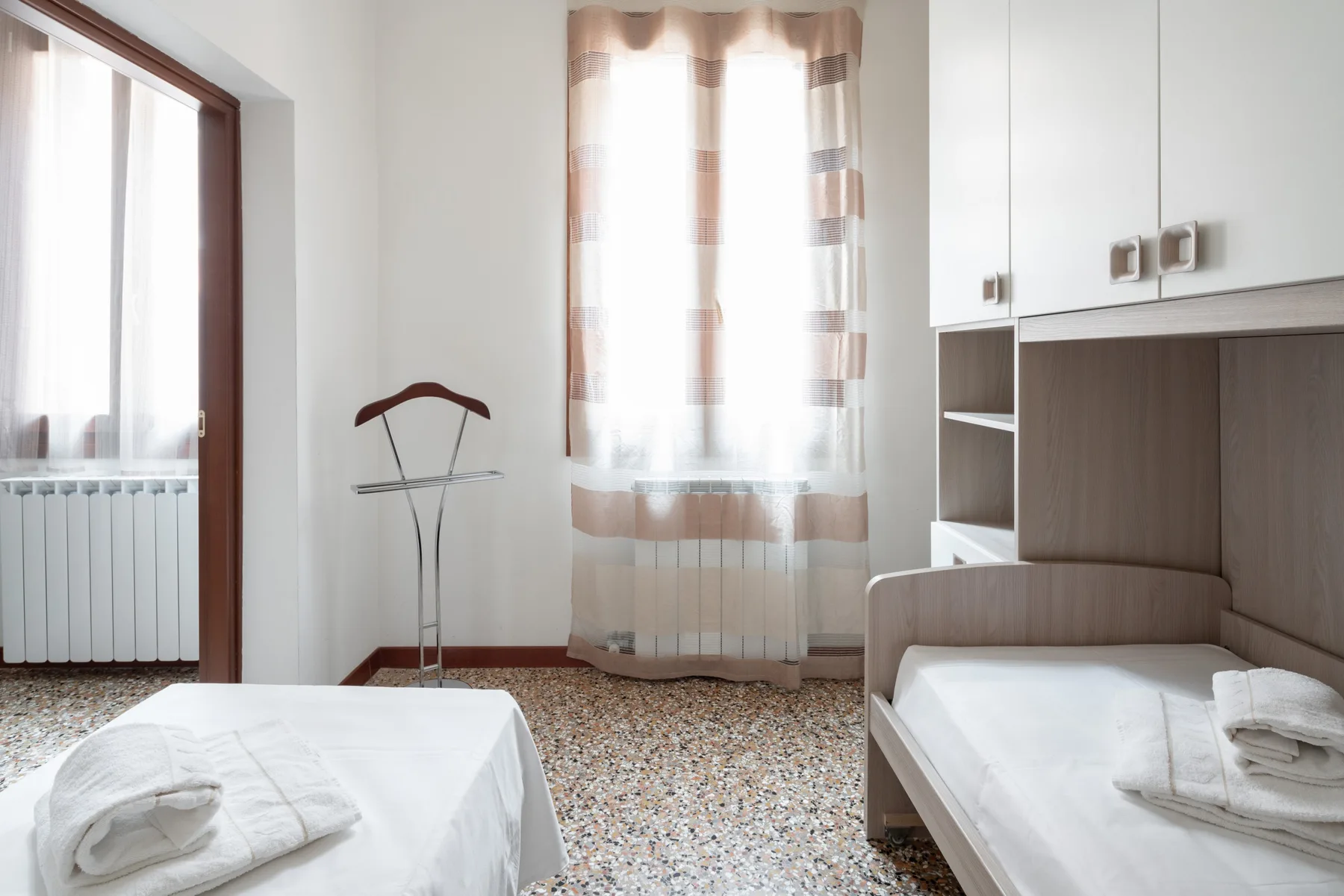 Un dormitorio luminoso con dos camas y una ventana grande.
