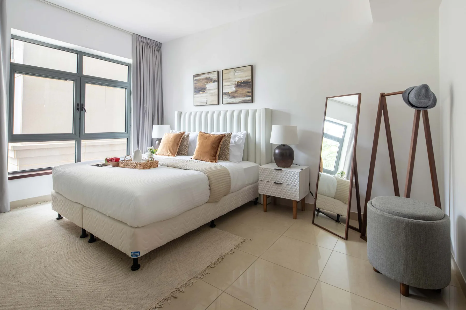 A bright bedroom with a large bed beside a tall window.