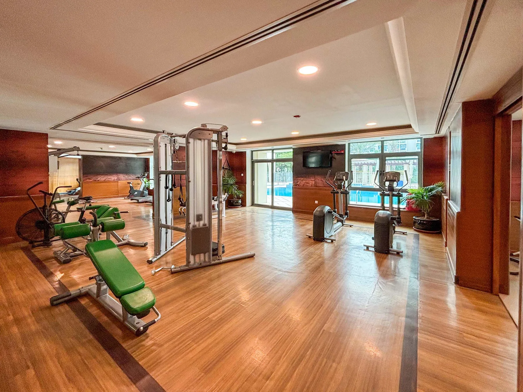 A spacious gym with exercise machines and benches on a wood floor.