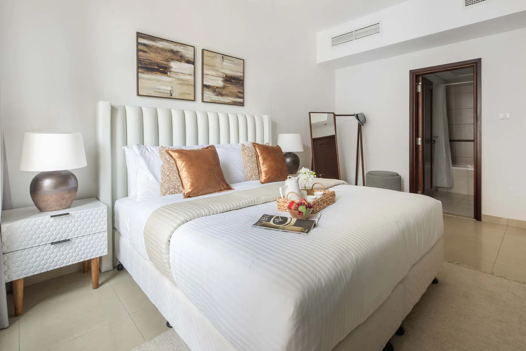 A bright bedroom with a large bed, bedside tables, and framed artwork.