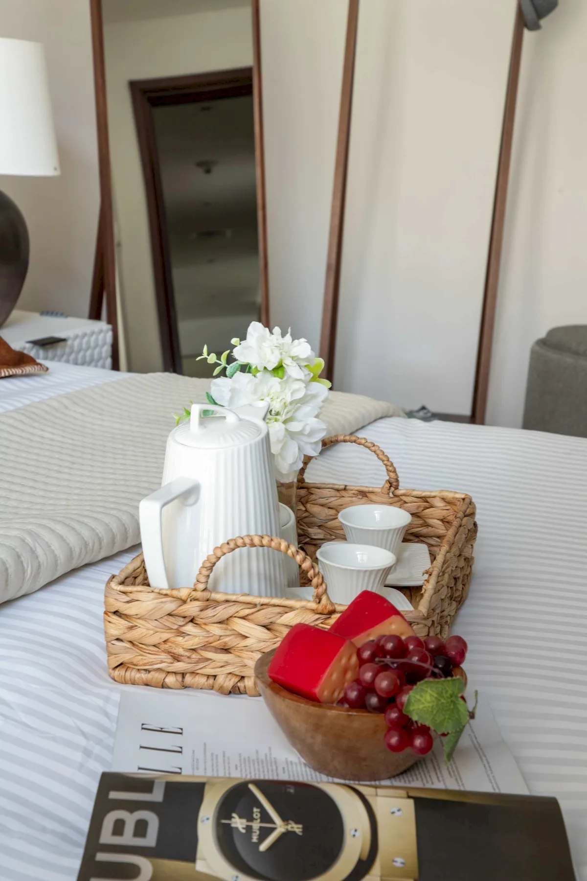 A bedroom with a neatly made bed and a tray of refreshments.