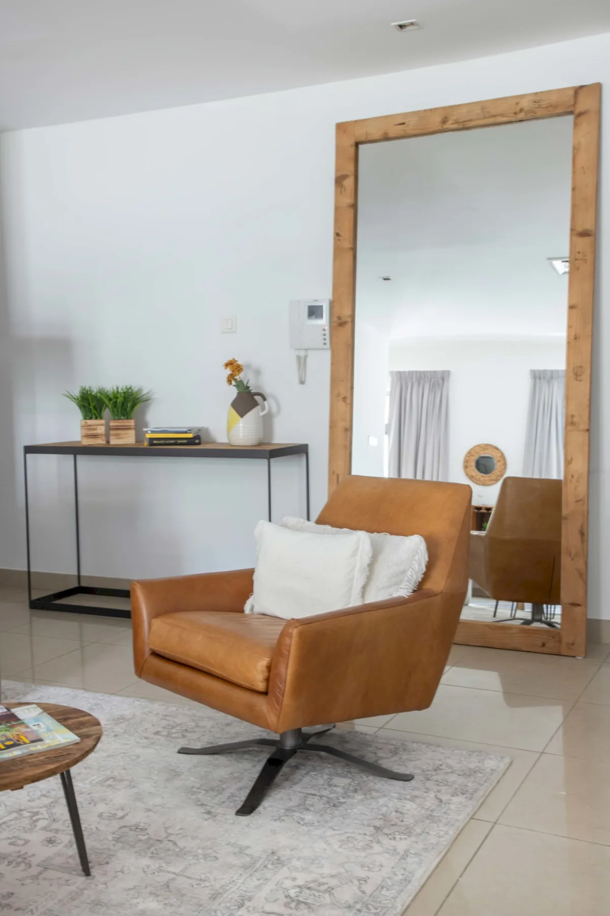 A sitting area with a brown armchair and a large wood-framed mirror.