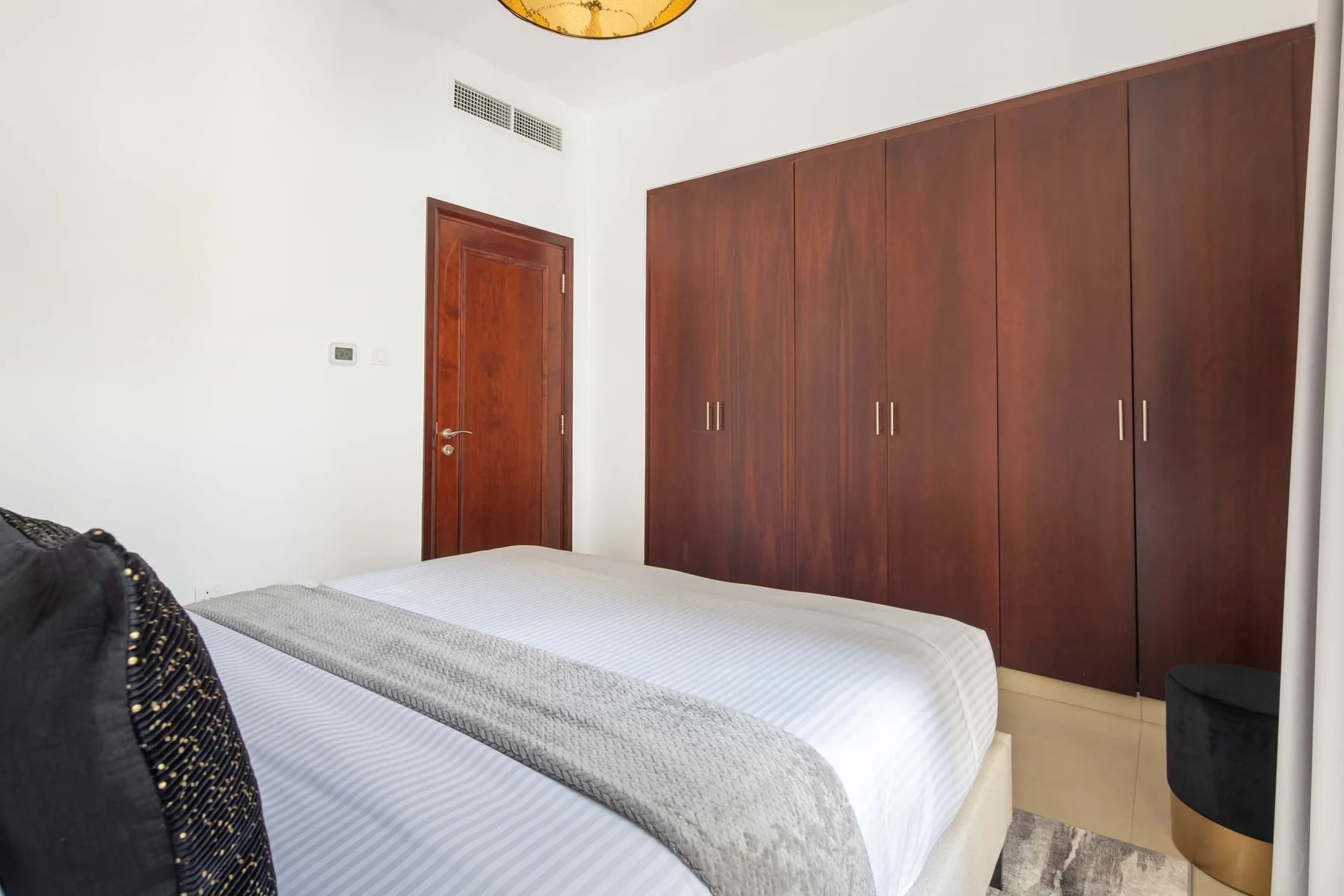 A bedroom with a large bed, a wooden wardrobe, and a wooden door.