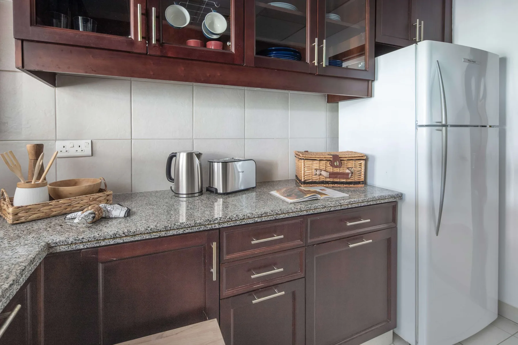 A kitchen with dark cabinets, a countertop, and a refrigerator.