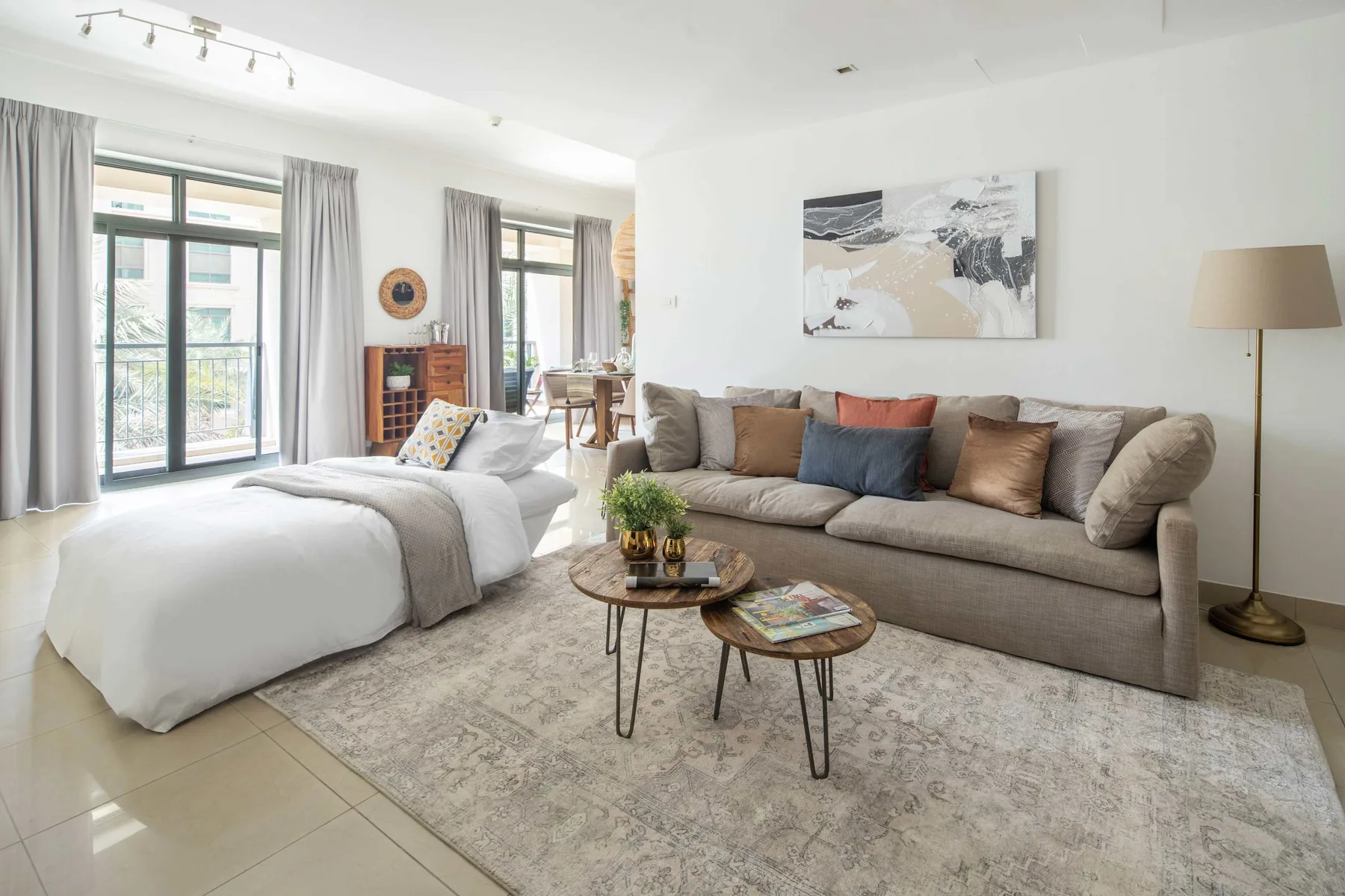 A bright bedroom and sitting area with a bed beside a large sofa.