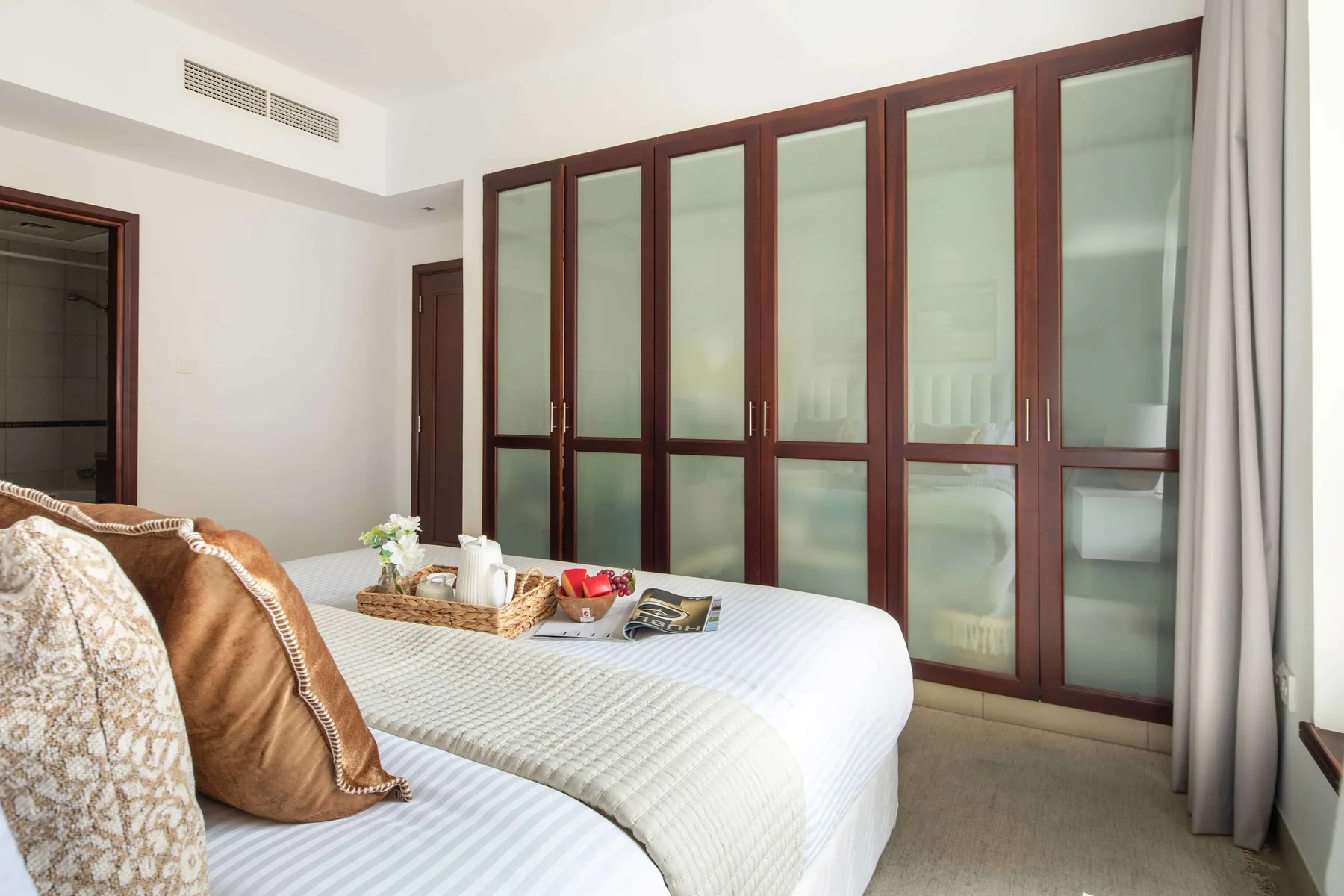 Bedroom with a bed, pillows, and tall frosted-glass wardrobes.