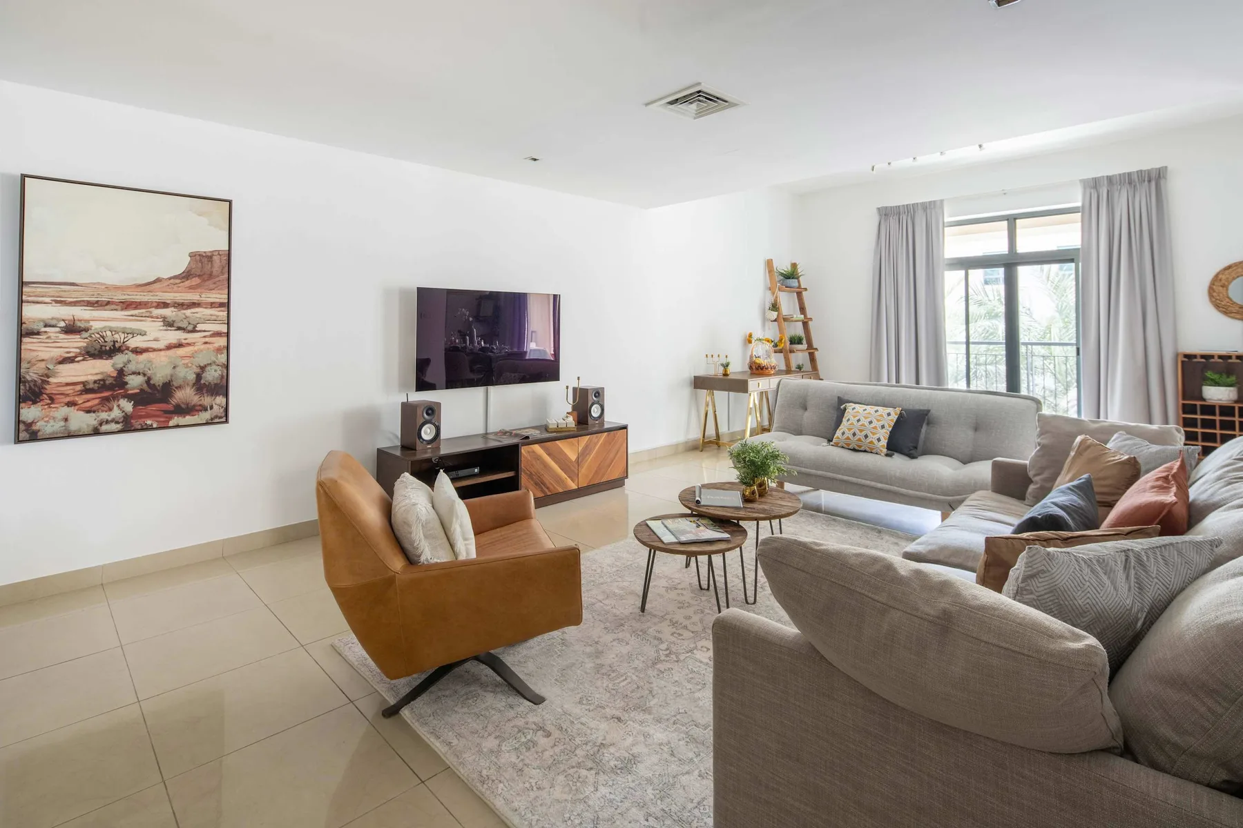 A bright living room with gray seating arranged around a television.