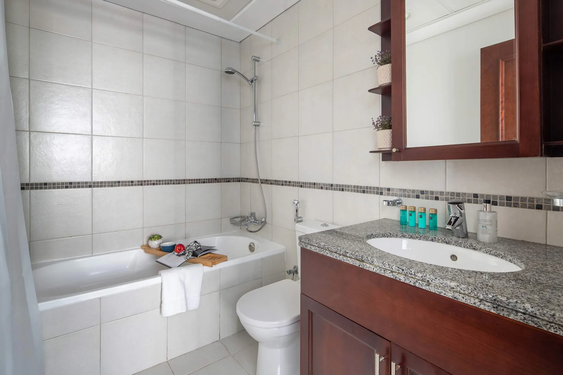 A tiled bathroom with a bathtub, toilet, and sink vanity.
