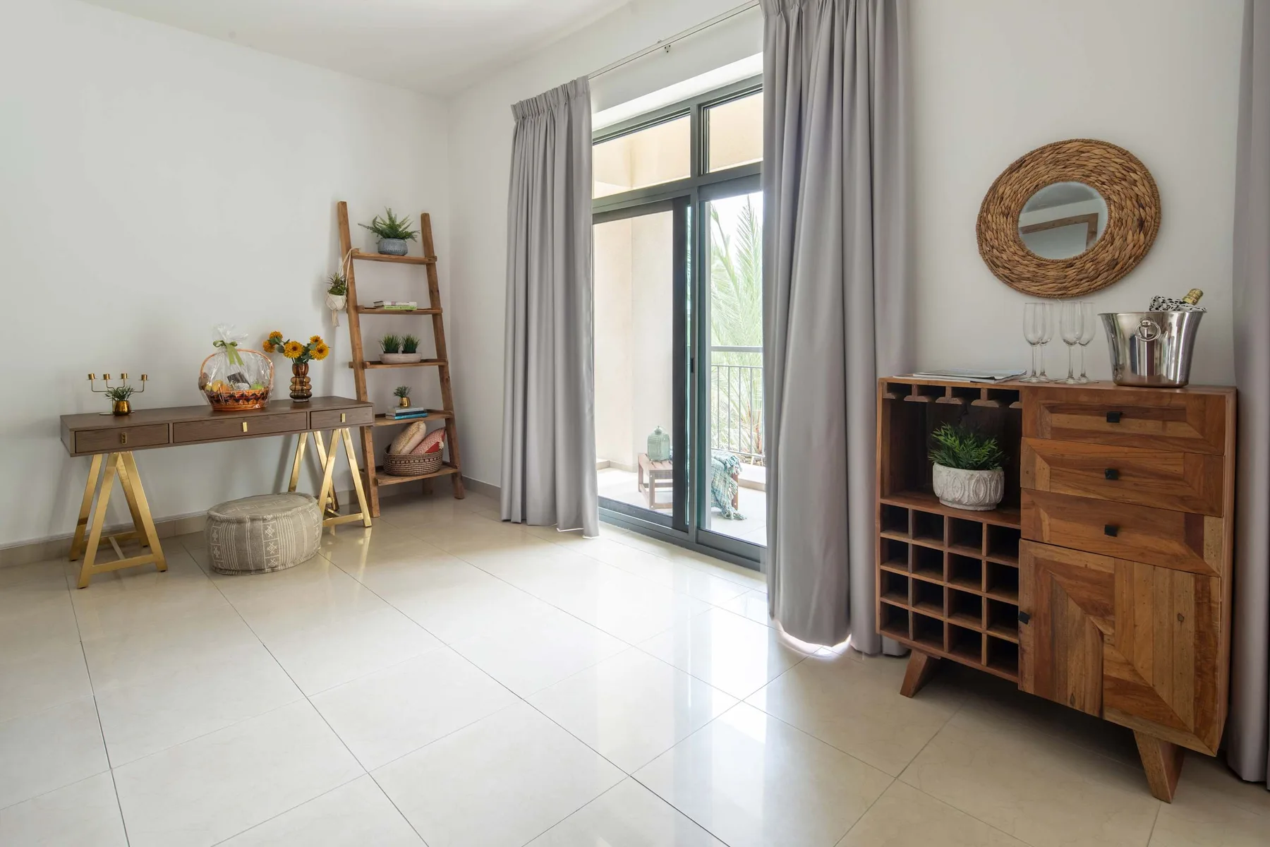 A bright room with a sliding glass door, gray curtains, and wooden furnishings.