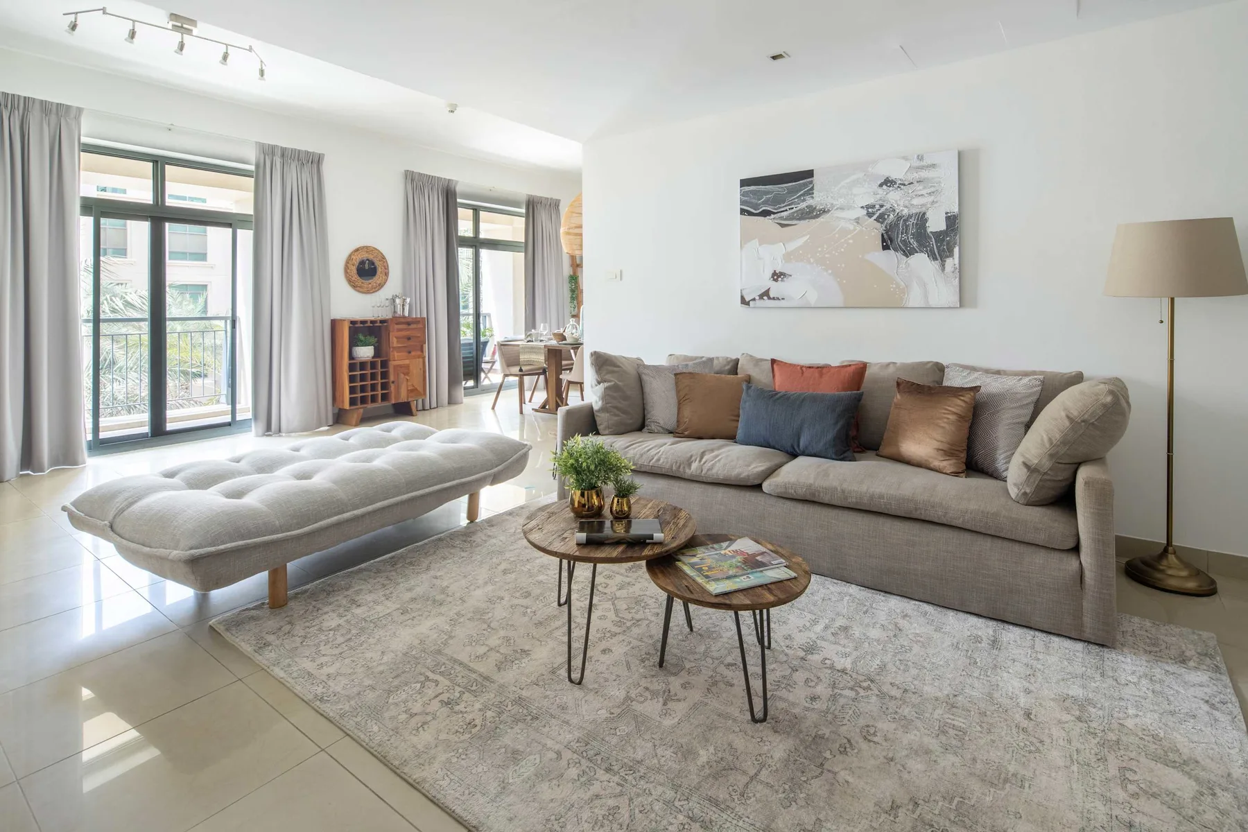 A bright living room with a sofa, coffee tables, and large windows.