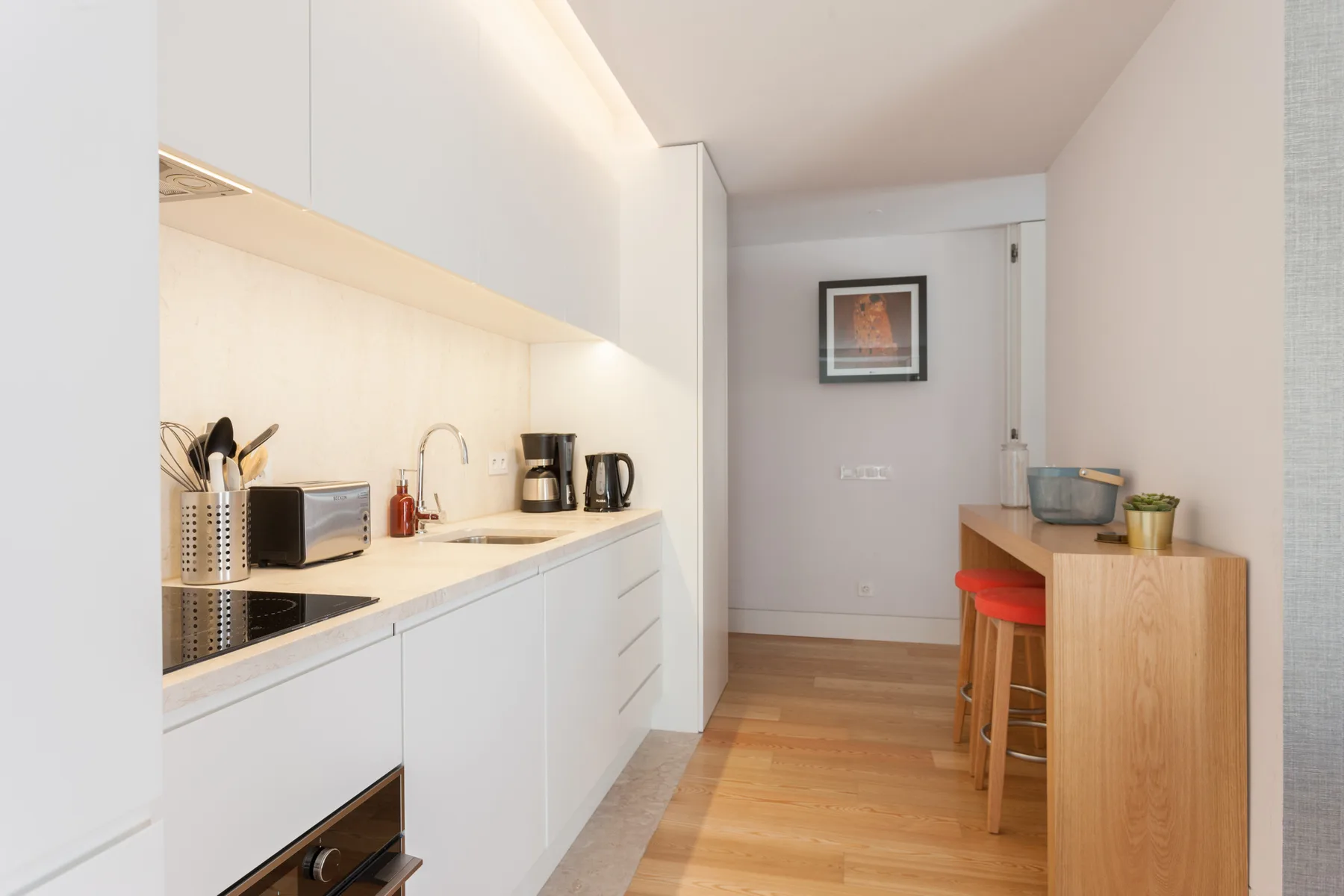 Una cocina compacta con gabinetes blancos y una barra de comedor de madera.