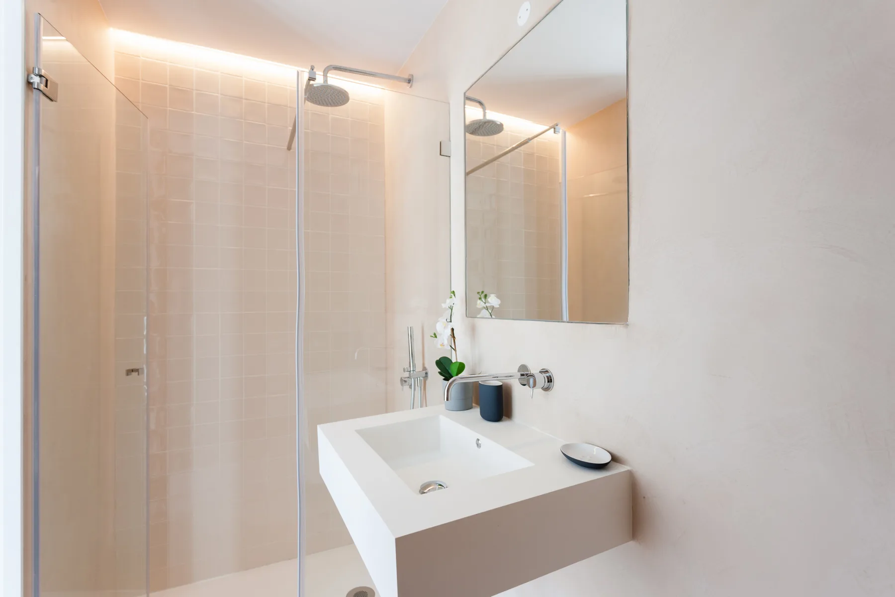 Un baño luminoso con ducha y lavabo suspendido.