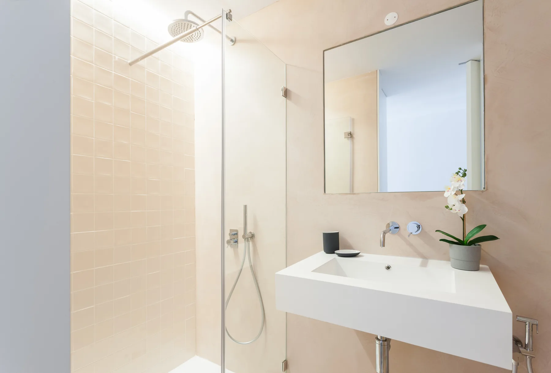 Un baño con ducha, espejo de pared y lavabo blanco.