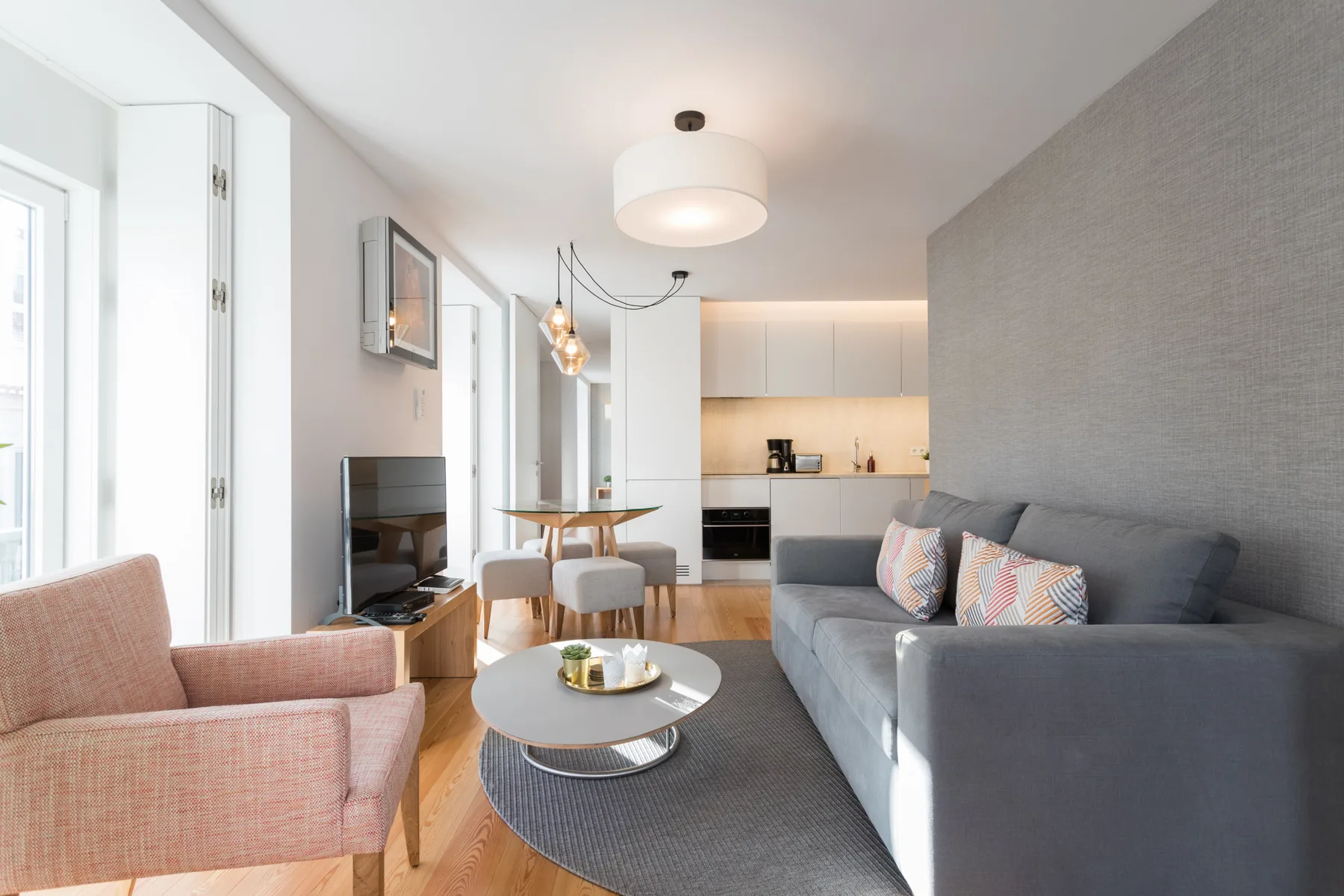 Una sala luminosa con asientos, una mesa de centro y una cocina abierta.