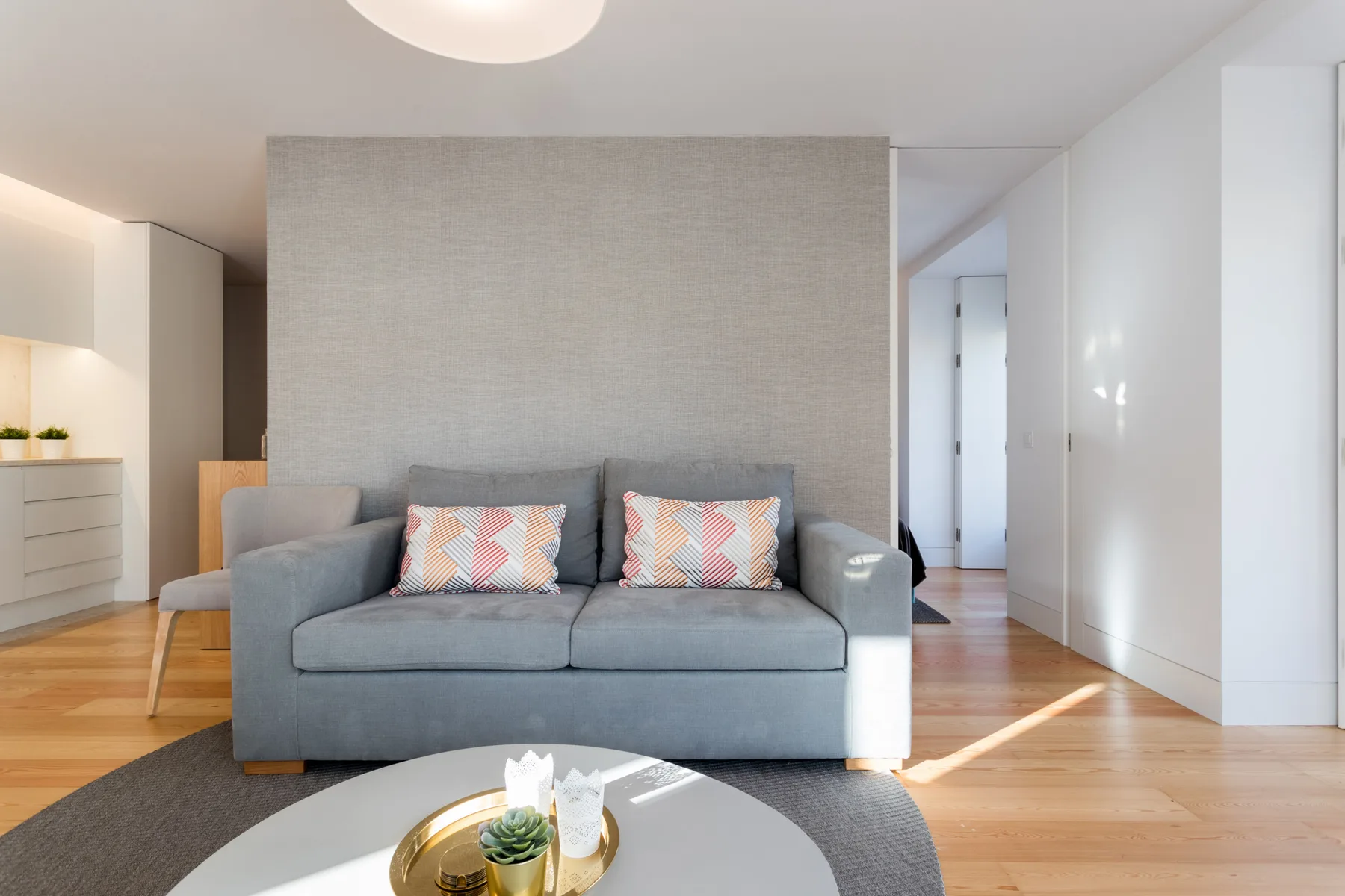 Una sala de estar con un sofá gris y una mesa de centro redonda.