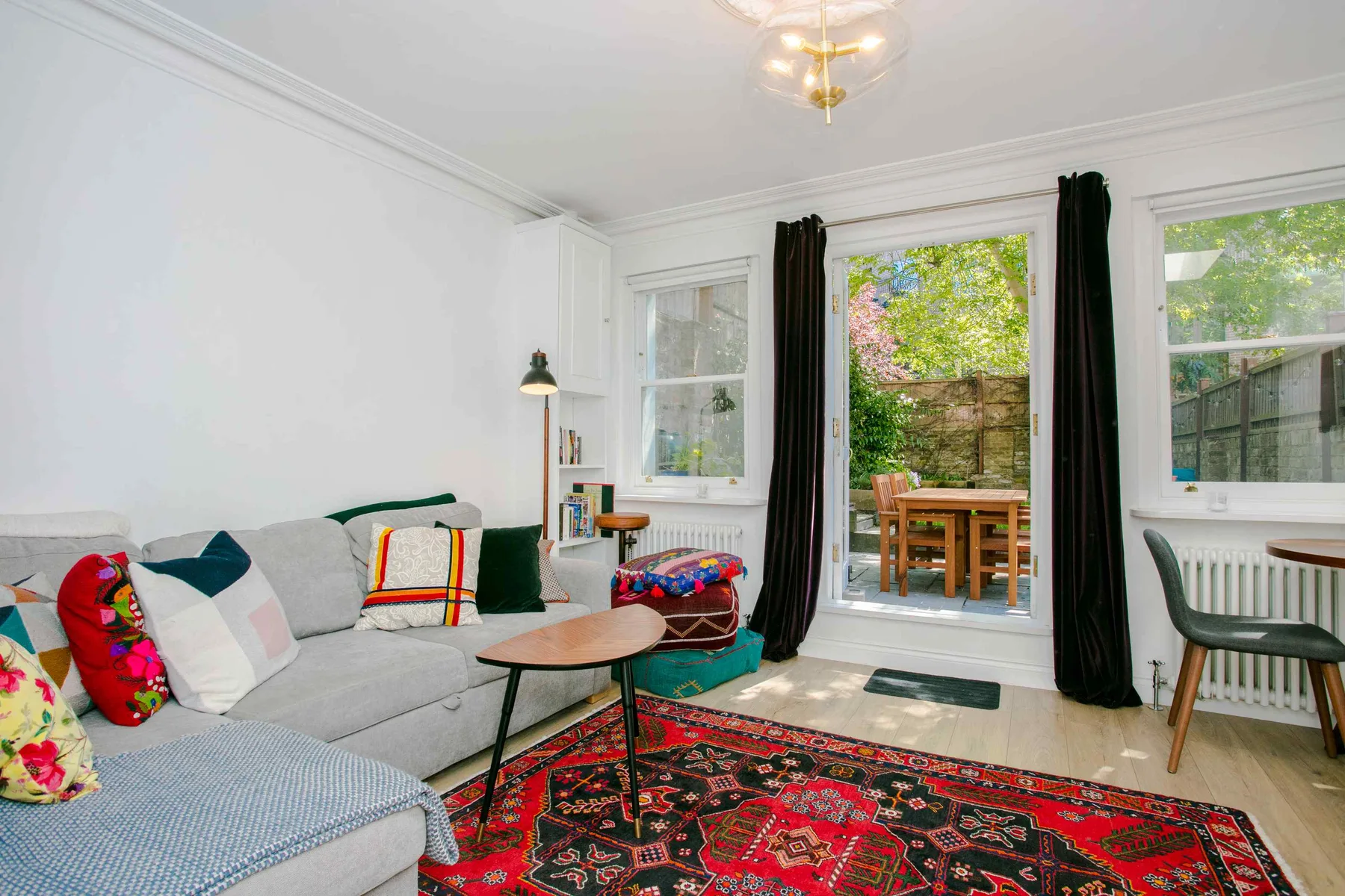 A bright living room with seating and an open door to a garden patio.