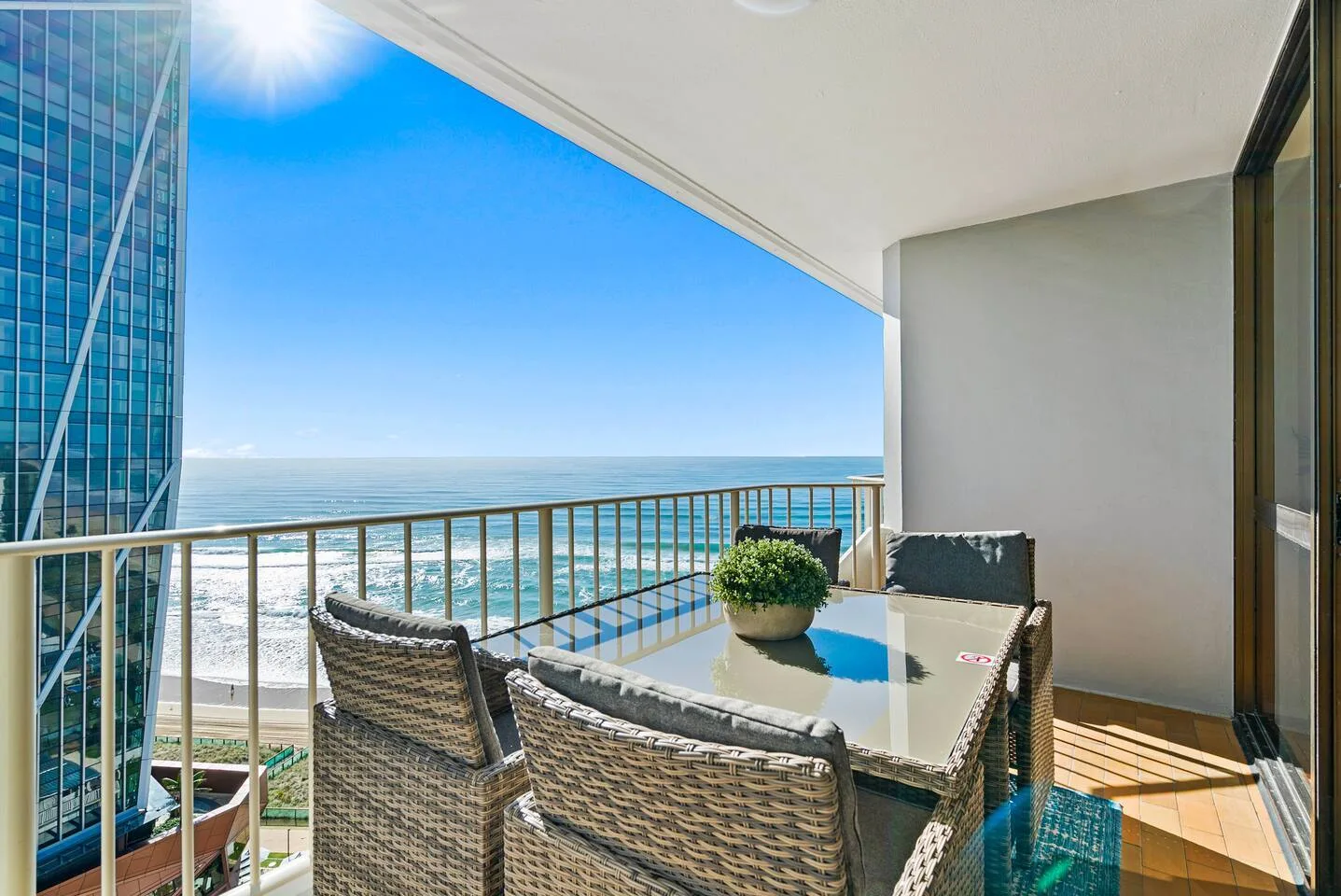 A balcony seating area overlooks the ocean, with a table and chairs.