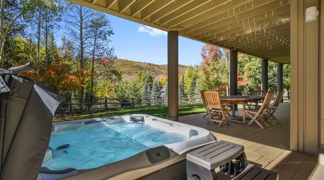 Una terraza cubierta cuenta con una bañera de hidromasaje y una mesa de comedor con sillas.