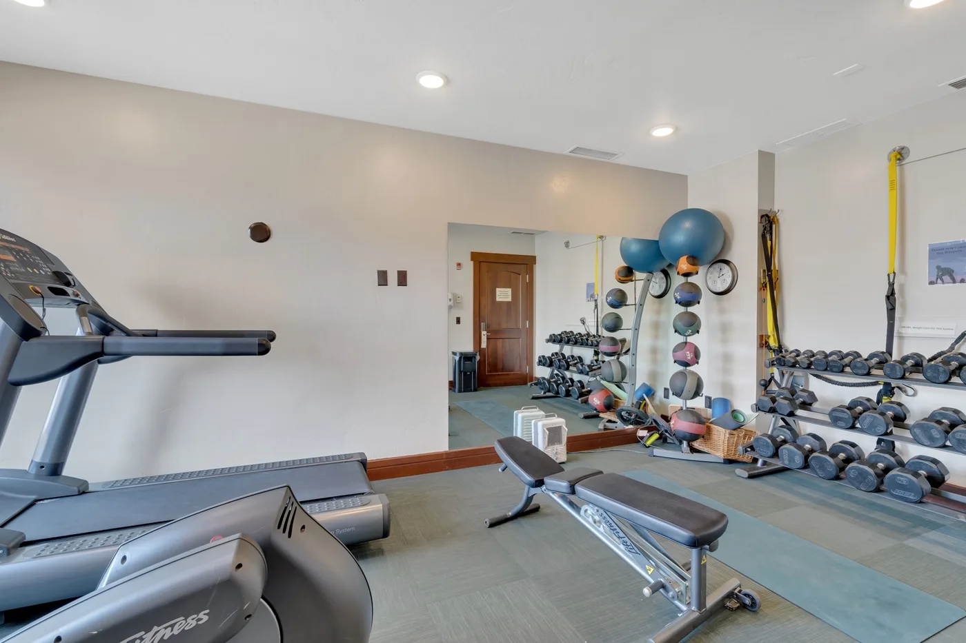 Un gimnasio con cintas de correr, pesas y bancos de ejercicio.