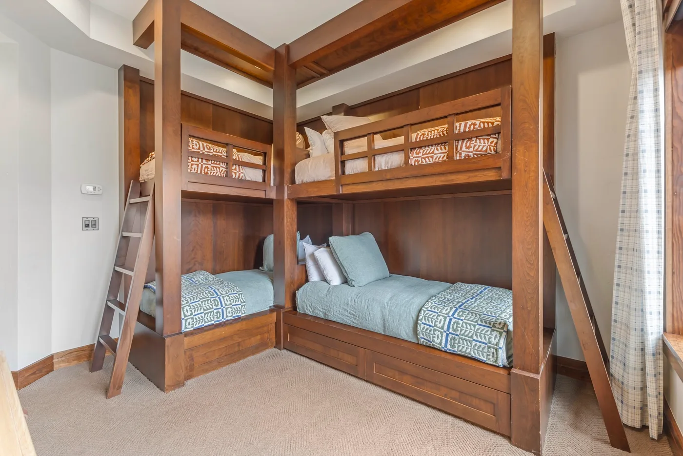 Un dormitorio con literas de madera y ropa de cama azul y estampada.