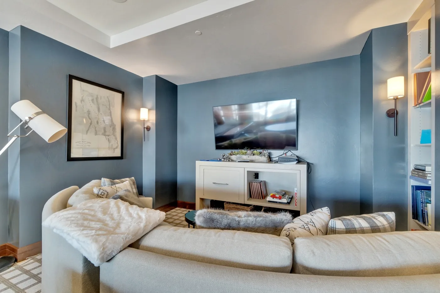 Una sala de estar con paredes azules, un televisor y asientos.