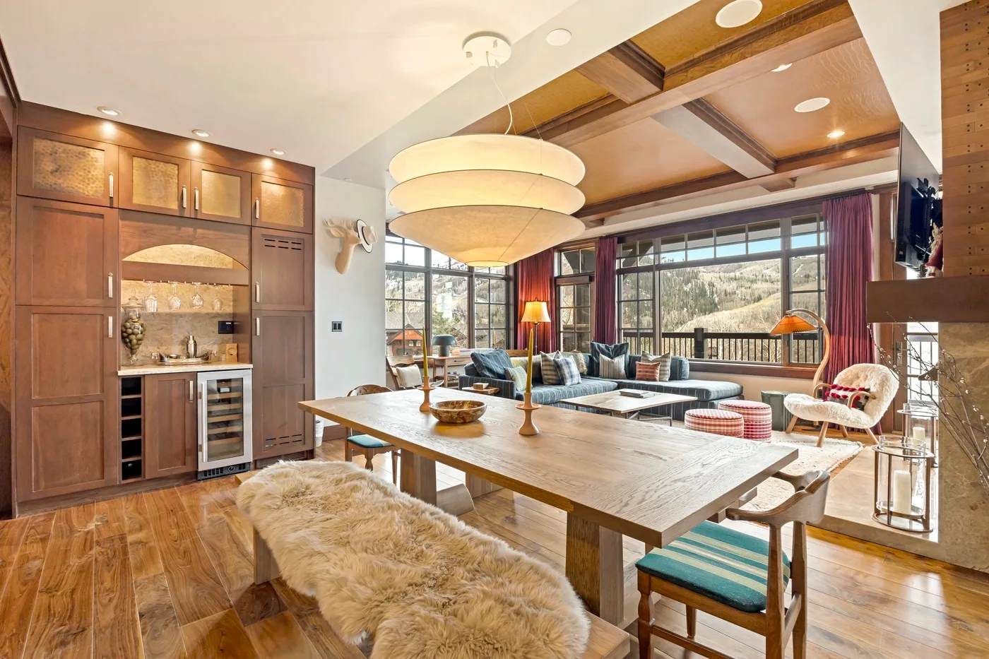 Comedor y sala de estar con una mesa larga de madera y grandes ventanales.