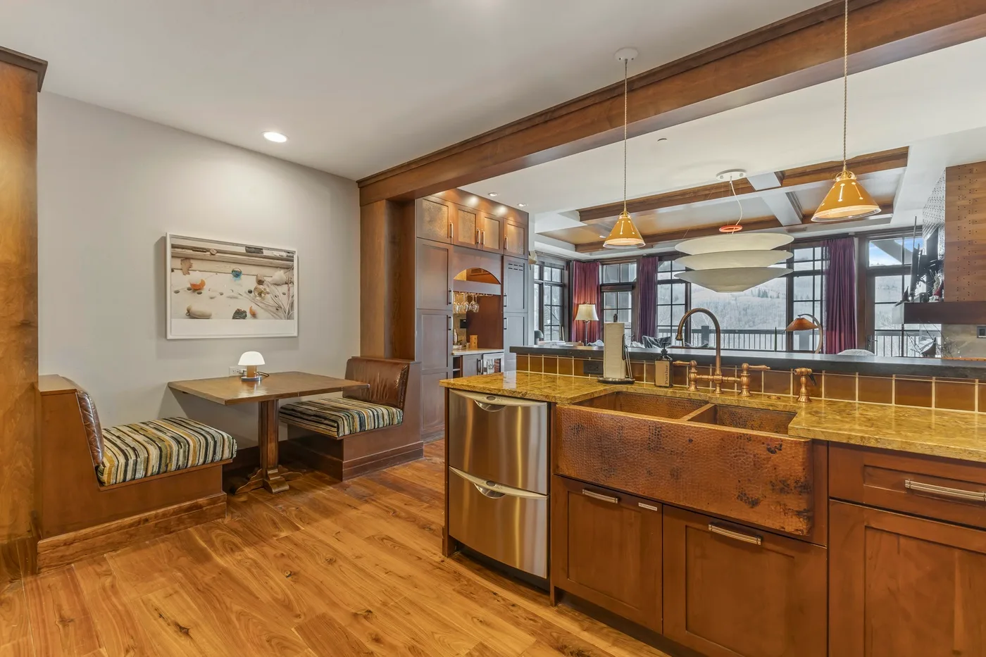 Una cocina y comedor de tonos cálidos, con gabinetes de madera y una mesa pequeña.
