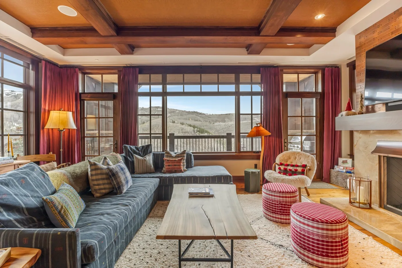 A living room with seating, a coffee table, and large windows overlooking a hillside.