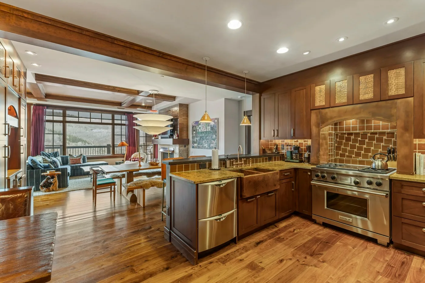 Una cocina con isla central, gabinetes de madera y una zona de estar contigua.