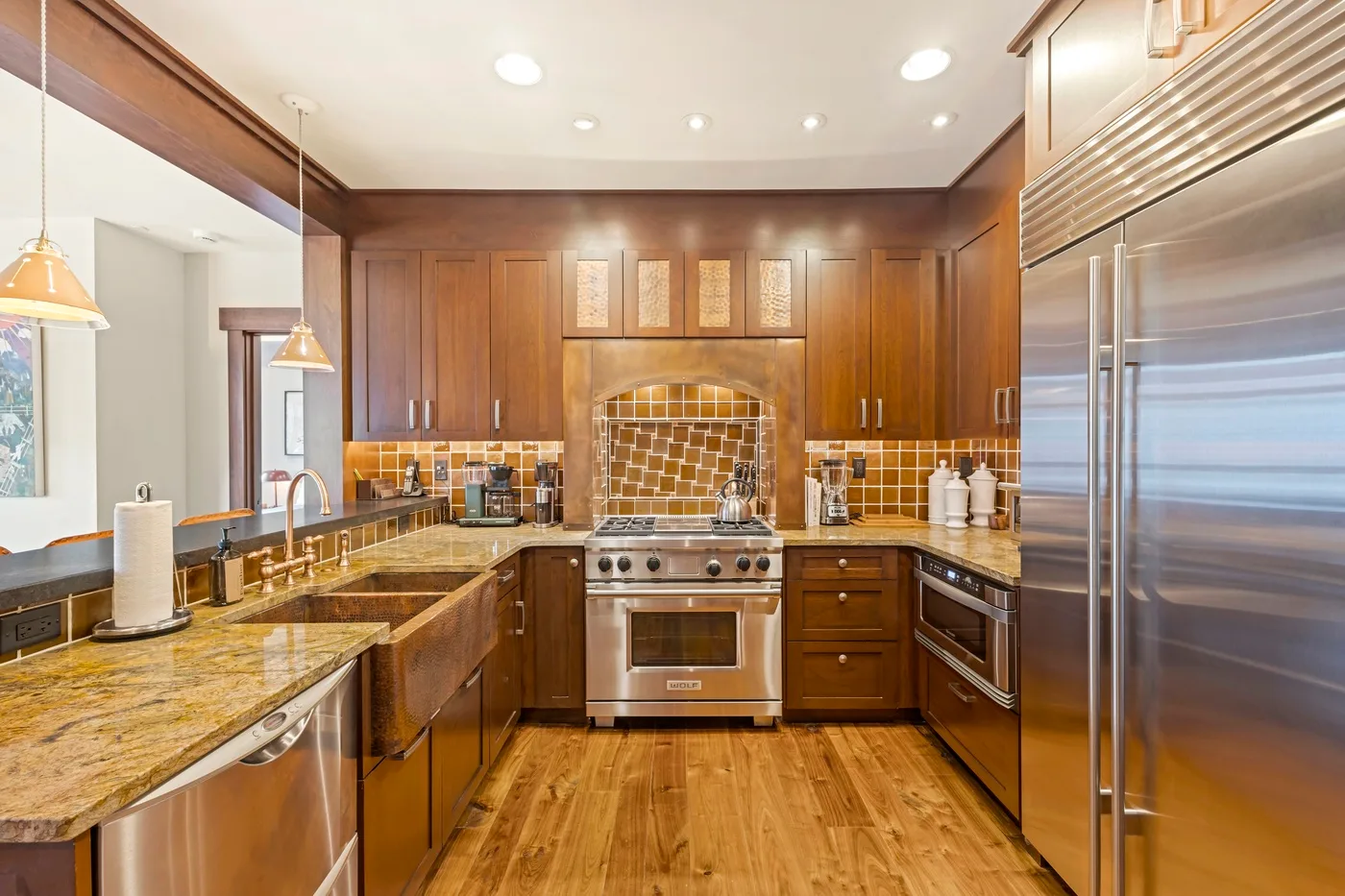 A spacious kitchen with wood cabinets, stone countertops, and stainless steel appliances.