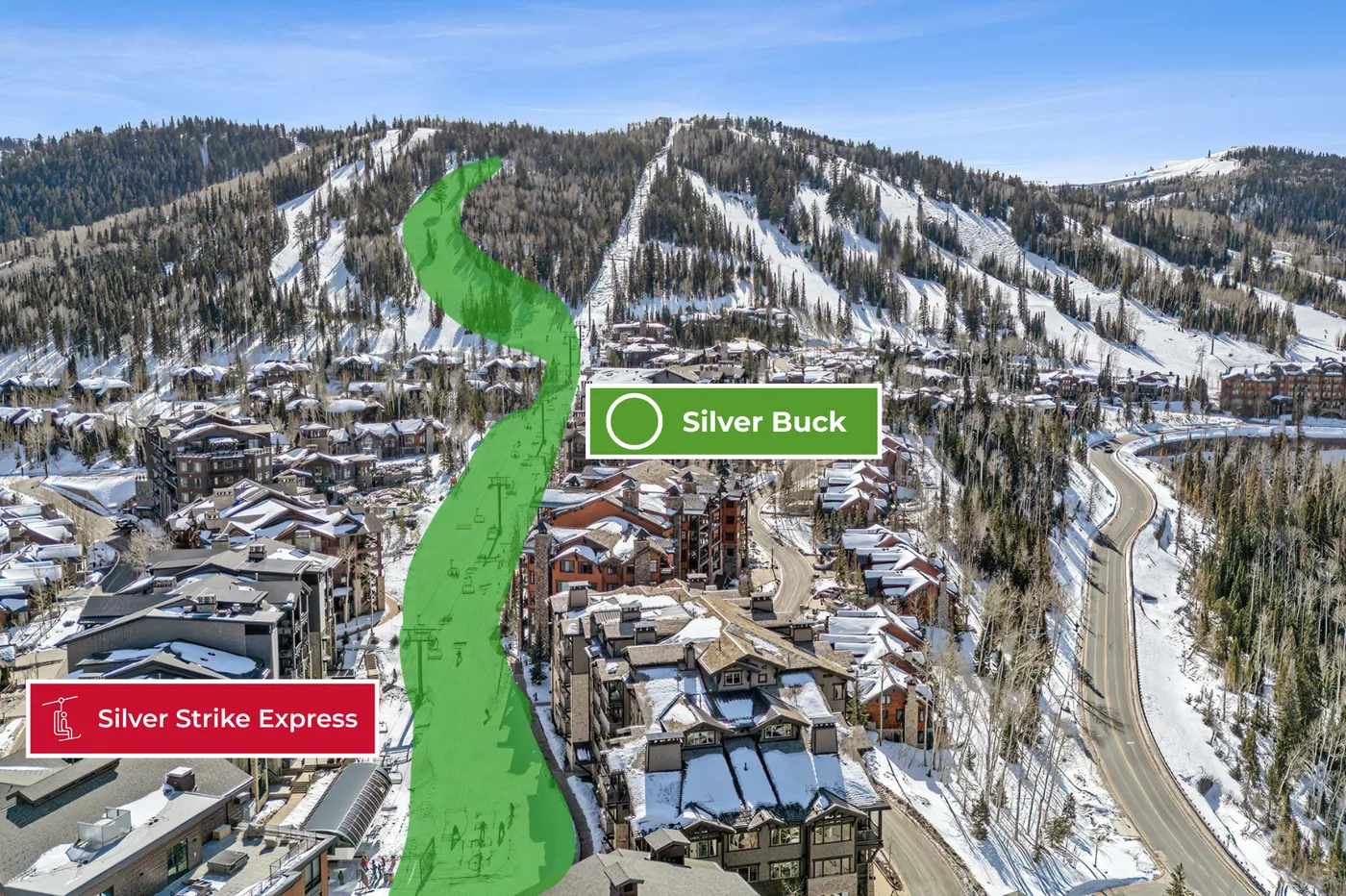 Vista aérea de un complejo de montaña nevado con una pista verde destacada entre los edificios.
