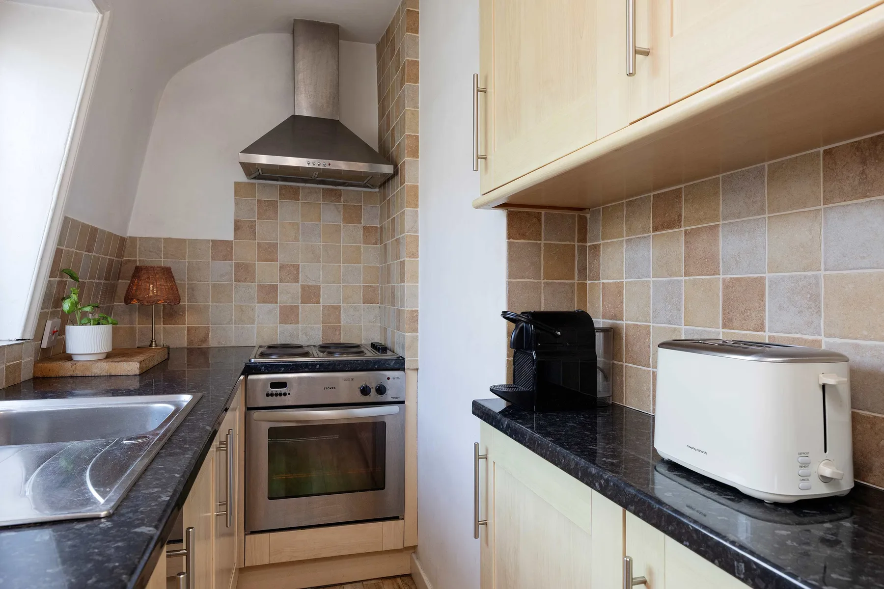 Una cocina compacta con una estufa de acero inoxidable y electrodomésticos sobre la encimera.