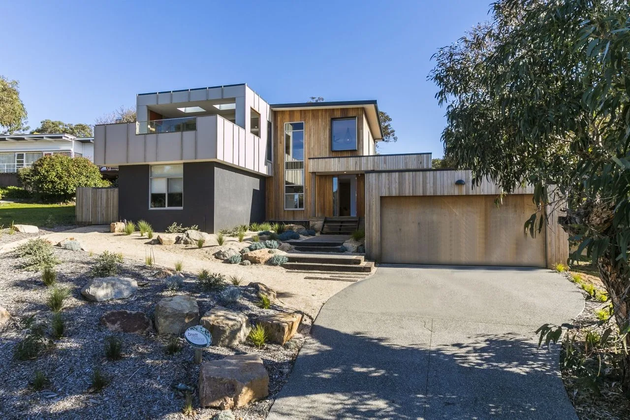 Exterior de una casa moderna con entrada para vehículos, jardín y garaje.