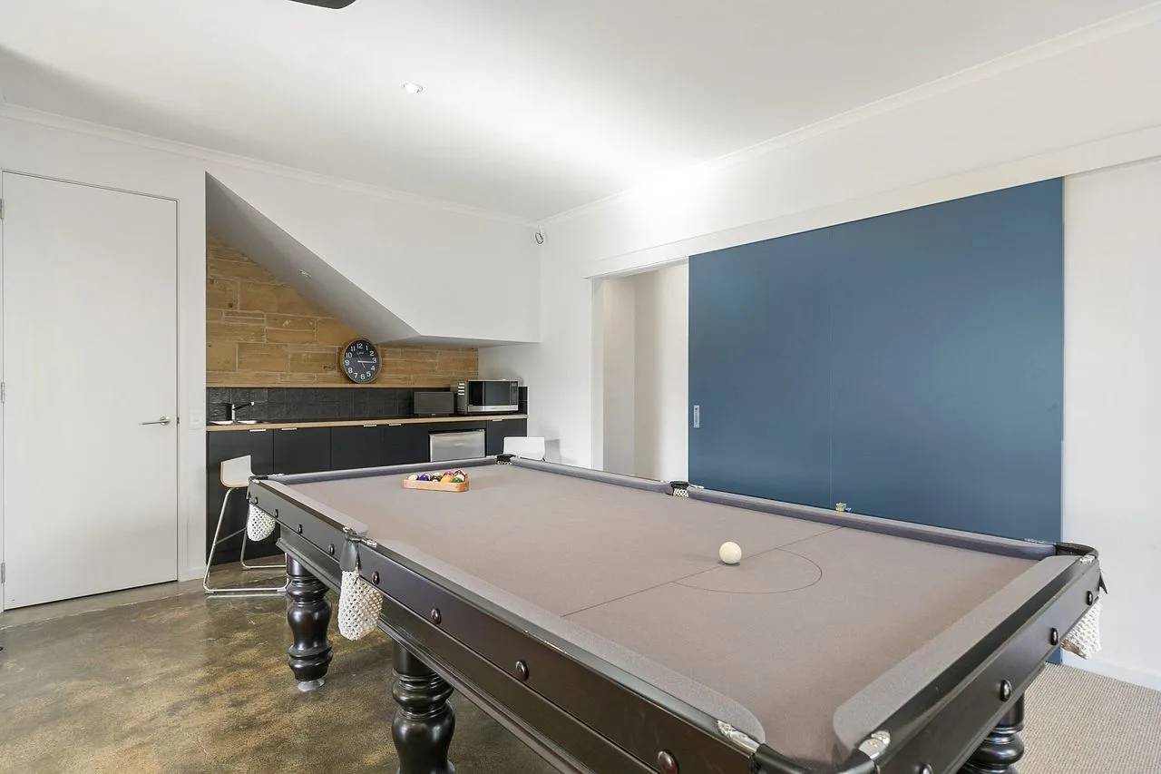 Sala de juegos con mesa de billar y cocina pequeña.