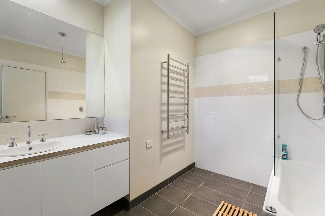 Un baño moderno con lavabo, espejo de pared y ducha.