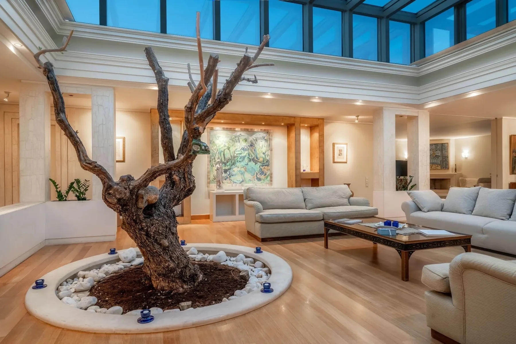 A bright living room with seating around a sculptural tree centerpiece.