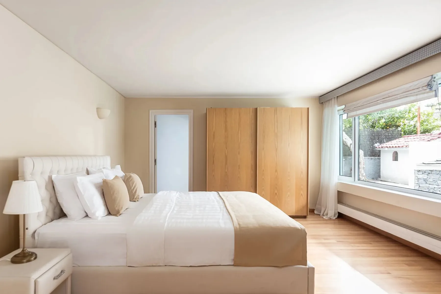 A bright bedroom with a bed and large windows.