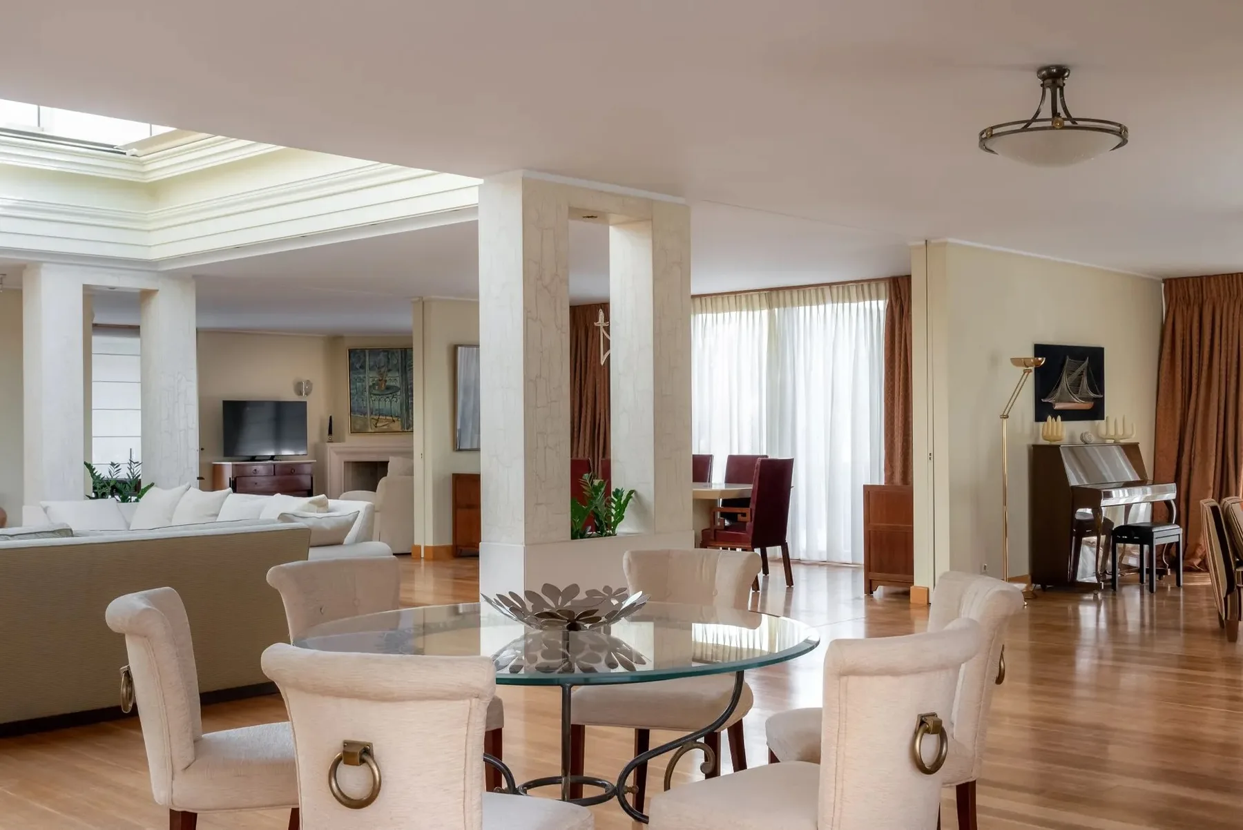 A bright open-plan living and dining room with a glass dining table and seating.