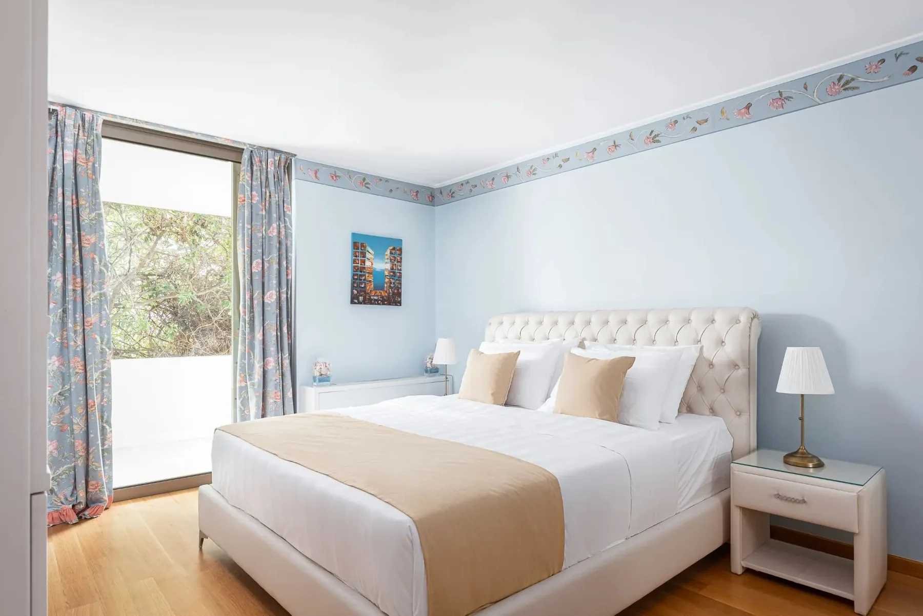 A bedroom with a large bed and floral curtains beside a glass door.
