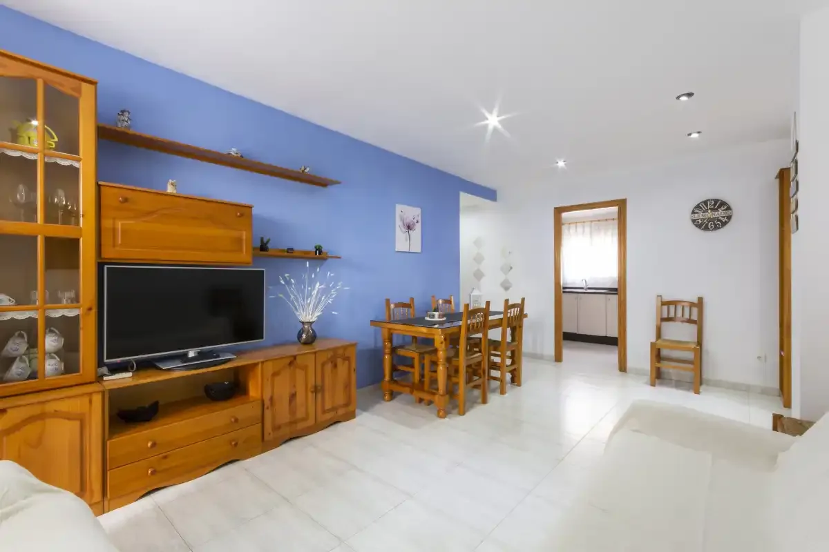 Una zona de estar y comedor con televisor, muebles de madera y una mesa de comedor.