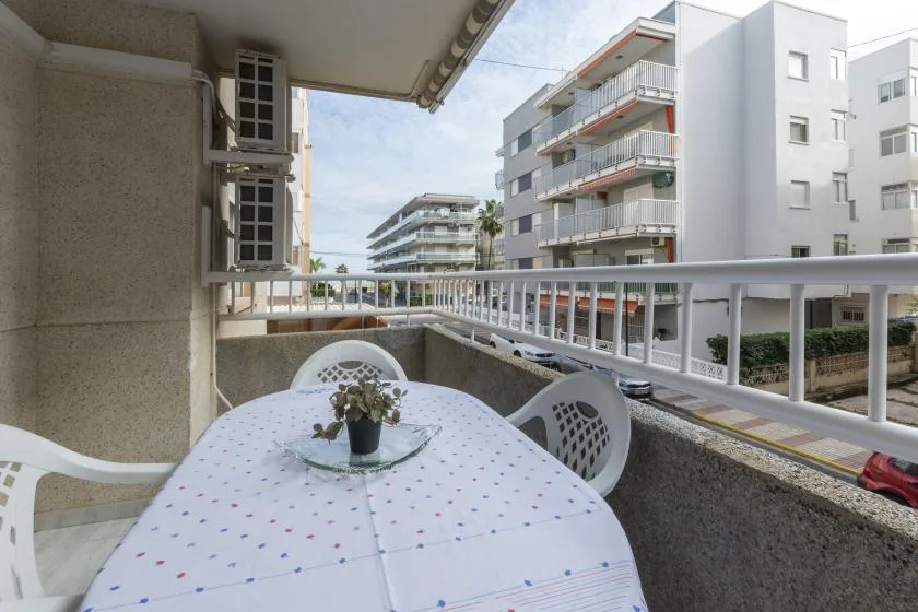 Una terraza al aire libre con mesa y asientos da a edificios de apartamentos cercanos.