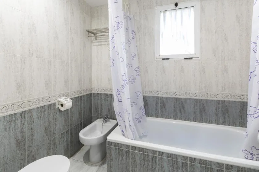 Un baño con bañera, cortina de ducha y bidé.
